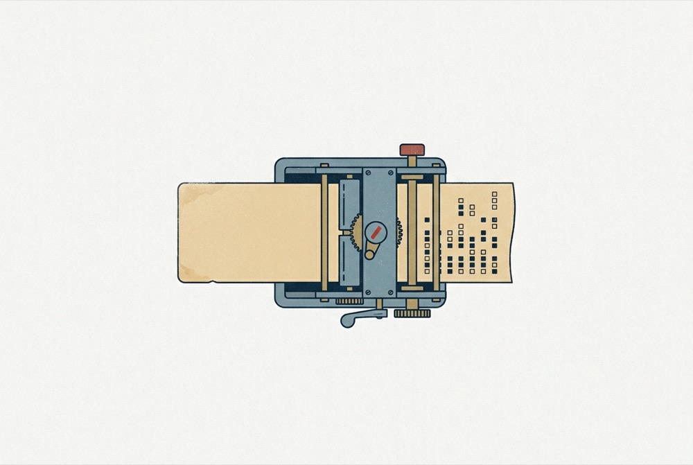 An index card feeds into a small machine and comes out the other side as a paper tape covered in rows of abstract square marks.